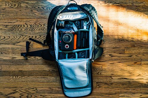 flat-lay photography of DSLR camera in backpack on wood parquet floor